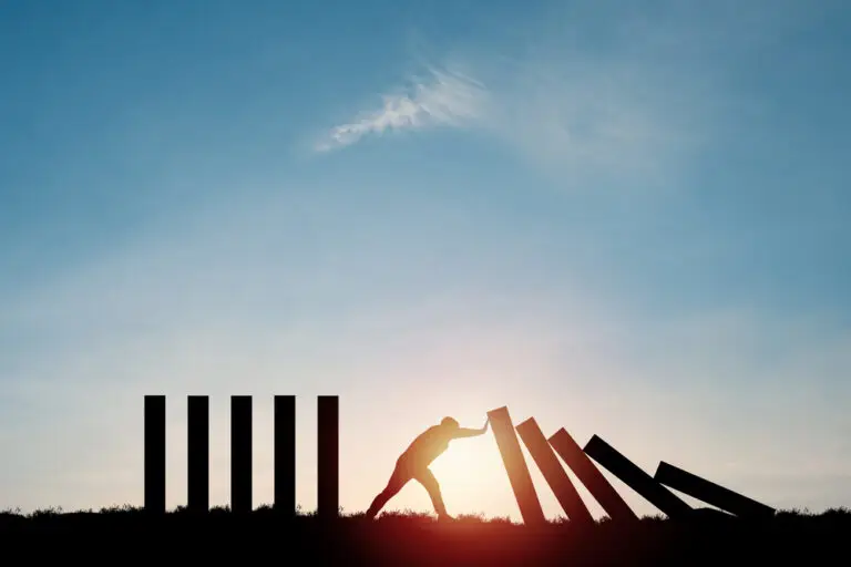Silhouette,Man,Pushing,Rectangle,Block,Which,Falling,To,Stop,Dominos