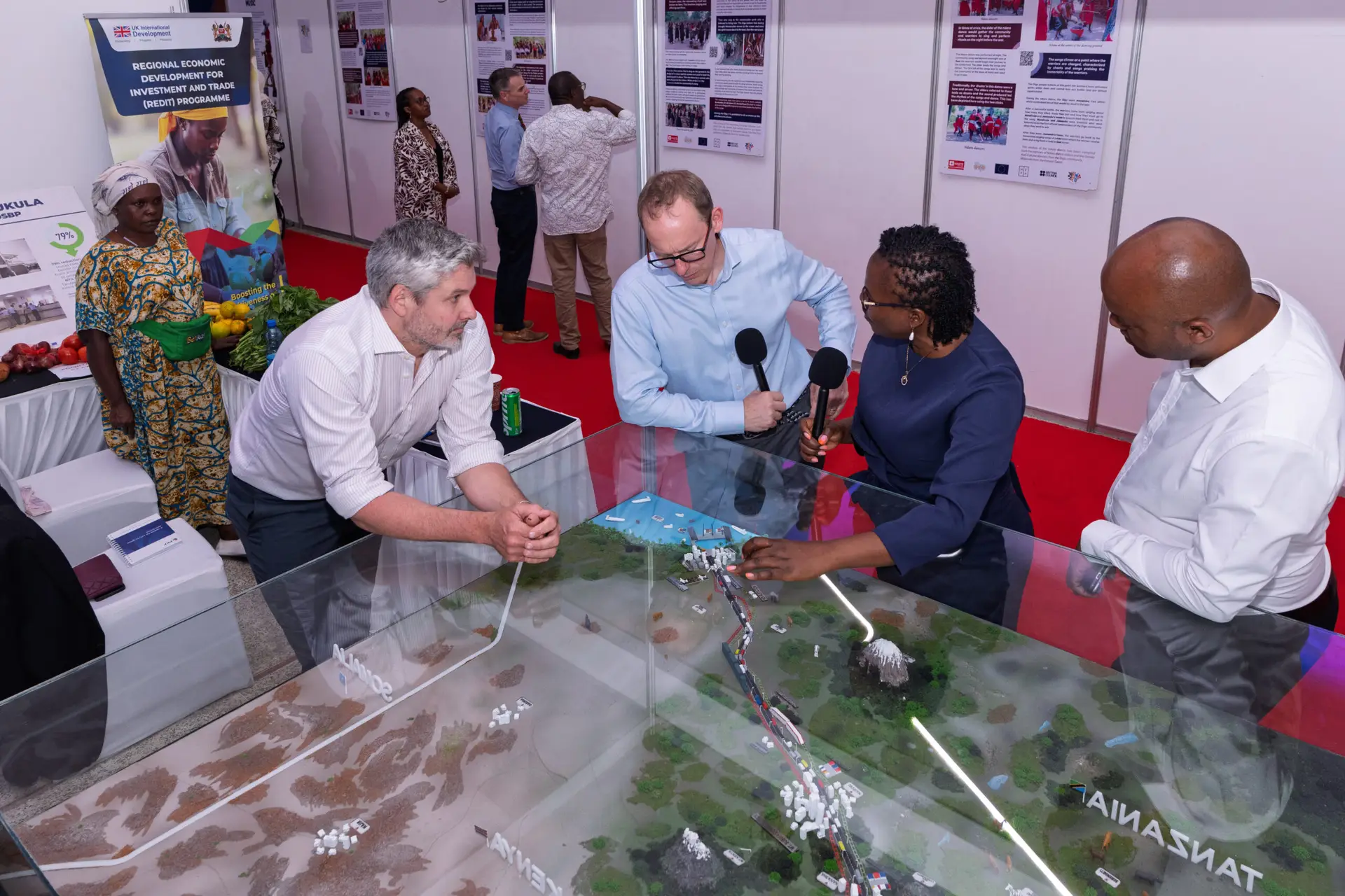 British High Commissioner Matt Baugh (in light blue shirt), alongside TMA CEO David Beer, explore TMA’s model of the Northern Corridor, which traces the journey of goods from the Port of Mombasa to Gulu in northern Uganda, at the British High Commission’s business expo in Mombasa on 13 October 2026.